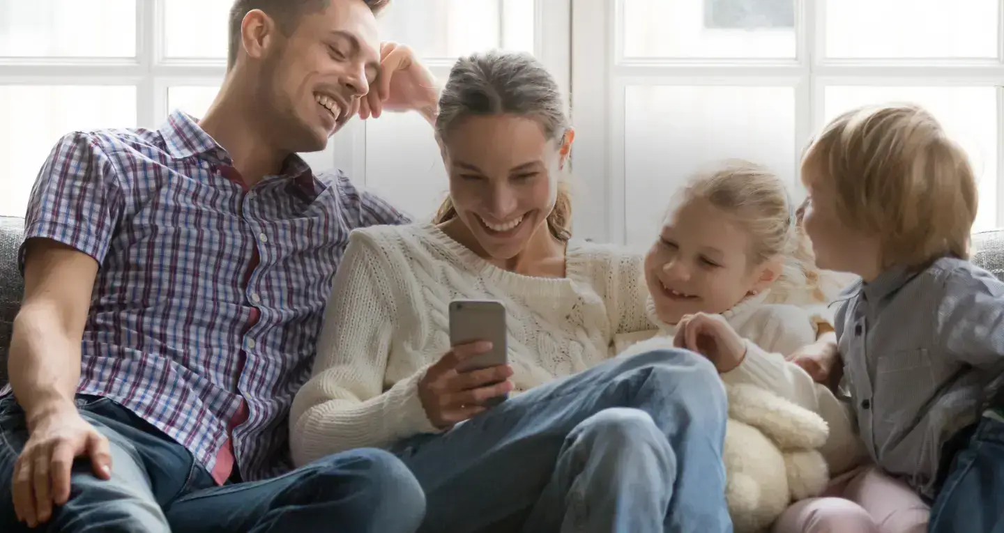 A family smiling together while looking at a phone